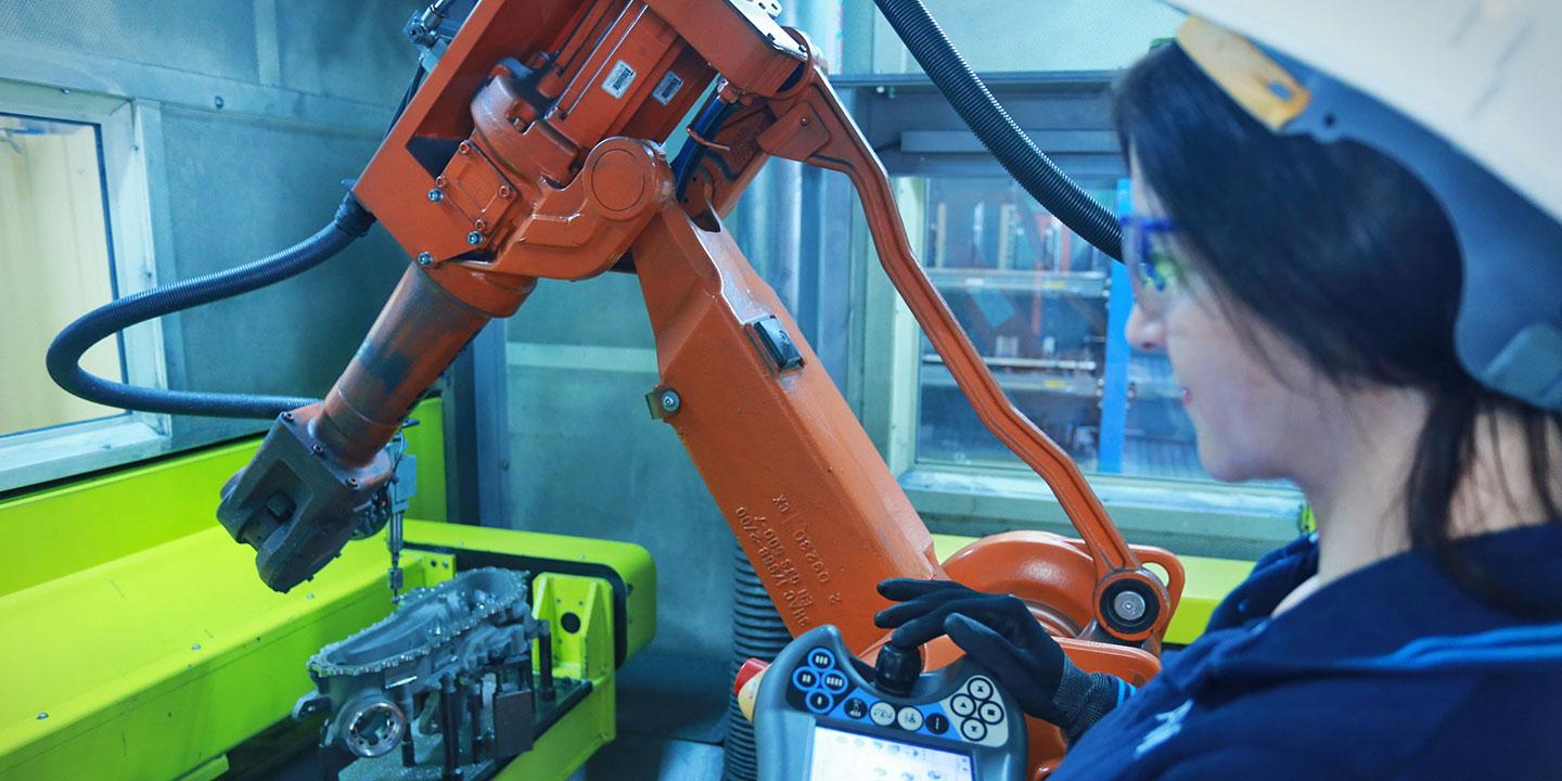 Zusammenarbeit von Mensch und Maschine: Eine Arbeiterin überprüft einen Roboter.
