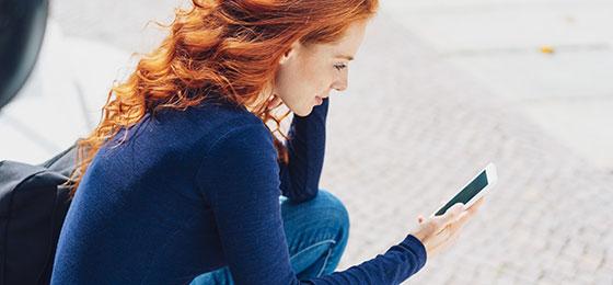 The image shows a young woman with a mobile phone.