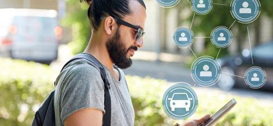 Das Bild zeigt einen Mann, der mit einem Tablet ein Carsharing-Fahrzeug bucht.