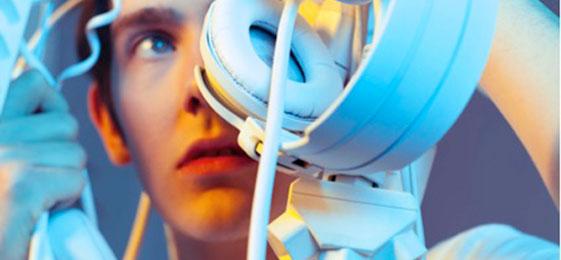 Das Foto zeigt einen jungen Mann mit einer grossen Anzahl elektronischer Geräte.