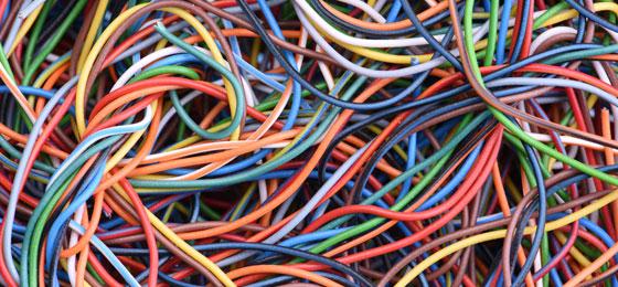 The picture shows a lot of old electricity and computer cables.